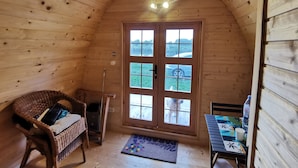 Une cabane en bois chaleureuse, dotée d'une grande fenêtre, de meubles en osier et d'une petite table avec un set de table.