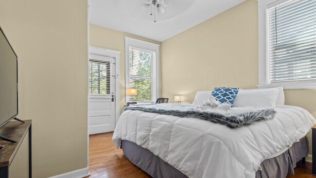 A bedroom with a bed, a desk, and a door leading to another room.