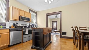 A modern kitchen with wooden cabinets, stainless steel appliances, and a dining area with a wooden table and chairs.
