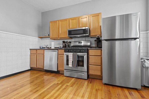 A kitchen with wooden cabinets, a stainless steel refrigerator, a microwave, an oven, and a dishwasher.
