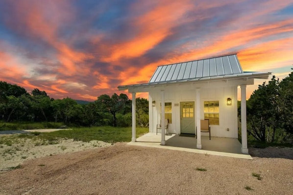A single-story house with a covered porch, a flat roof, and a small front yard.