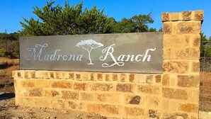 Skilt for Mudrona Ranch med et trælogo.
