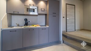 A modern kitchen with grey cabinets, a built-in microwave, and a coffee machine. - Matteotti Luxury Residence (Syracuse)