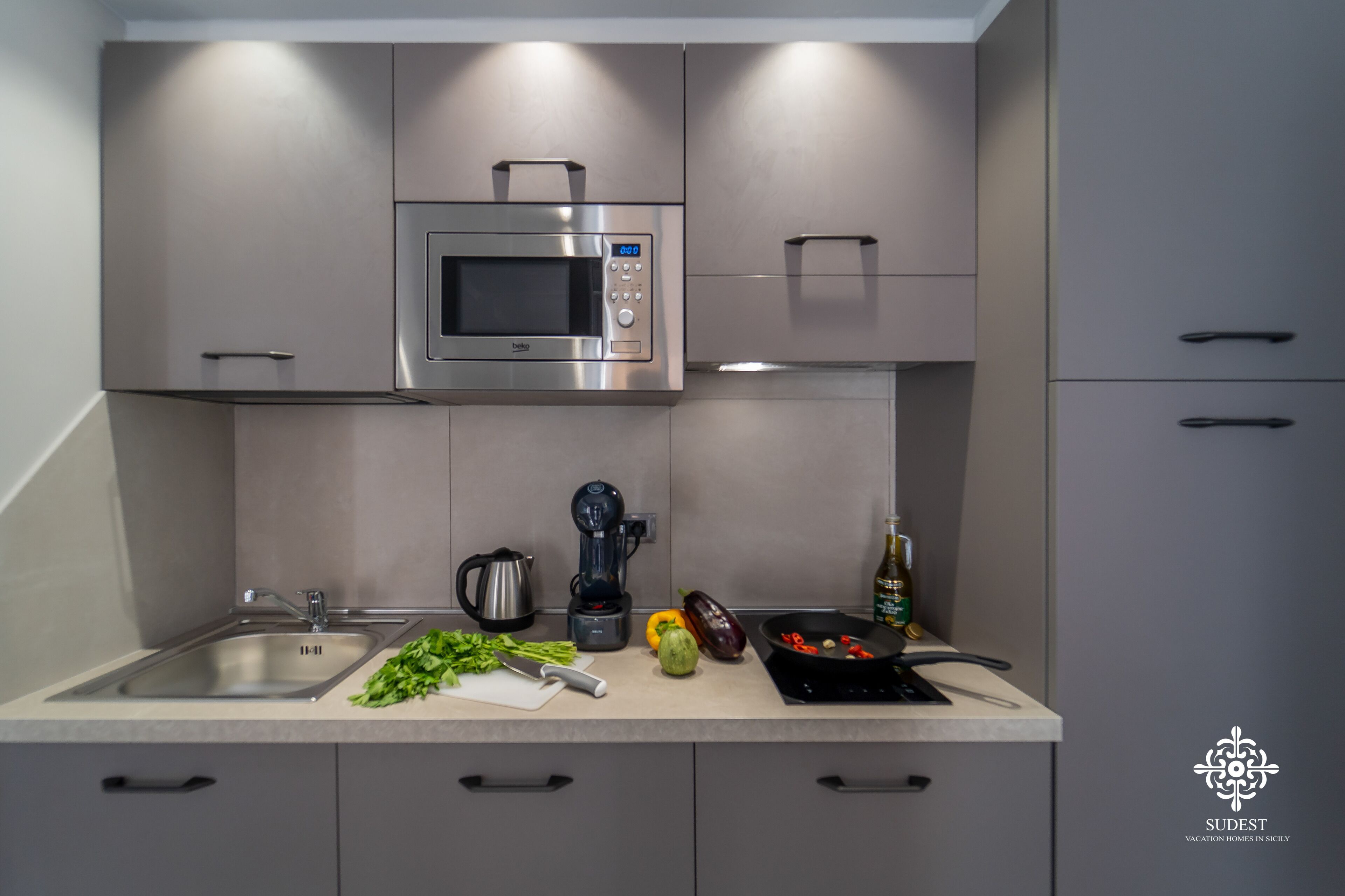 A modern kitchen with a built-in microwave, a coffee maker, and various vegetables on the counter.