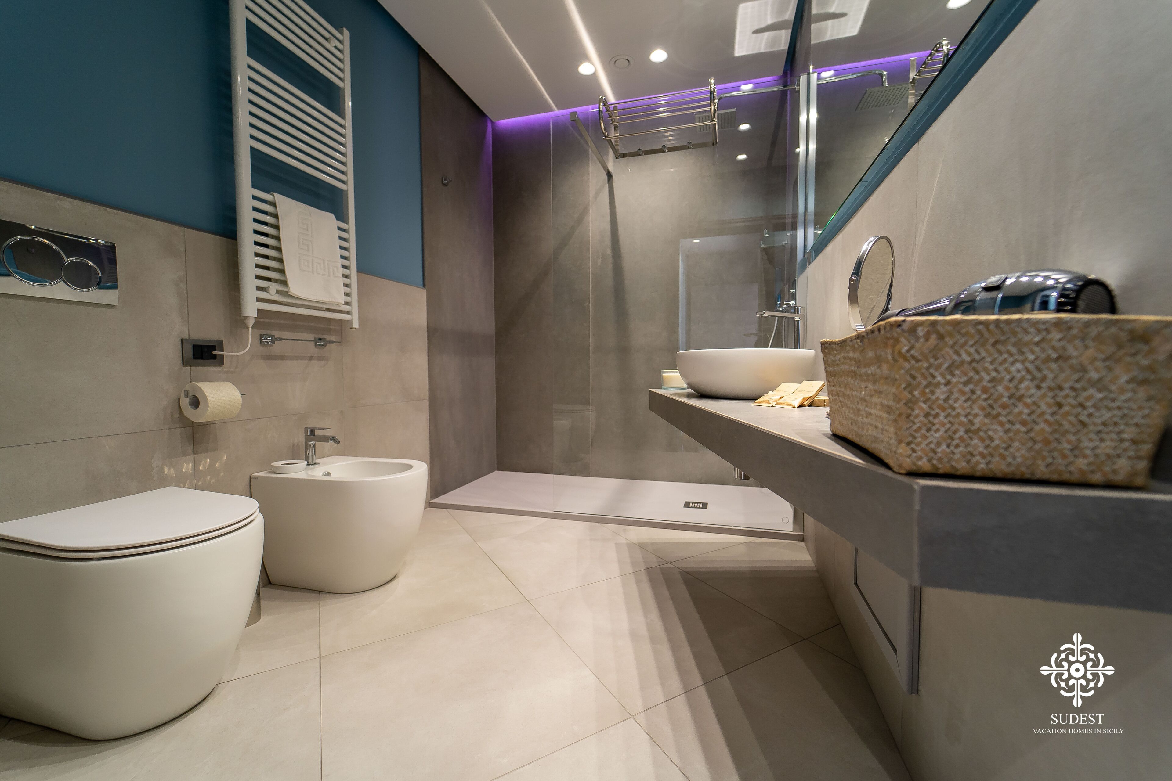 Une salle de bain moderne avec des toilettes, un bidet et un grand miroir.