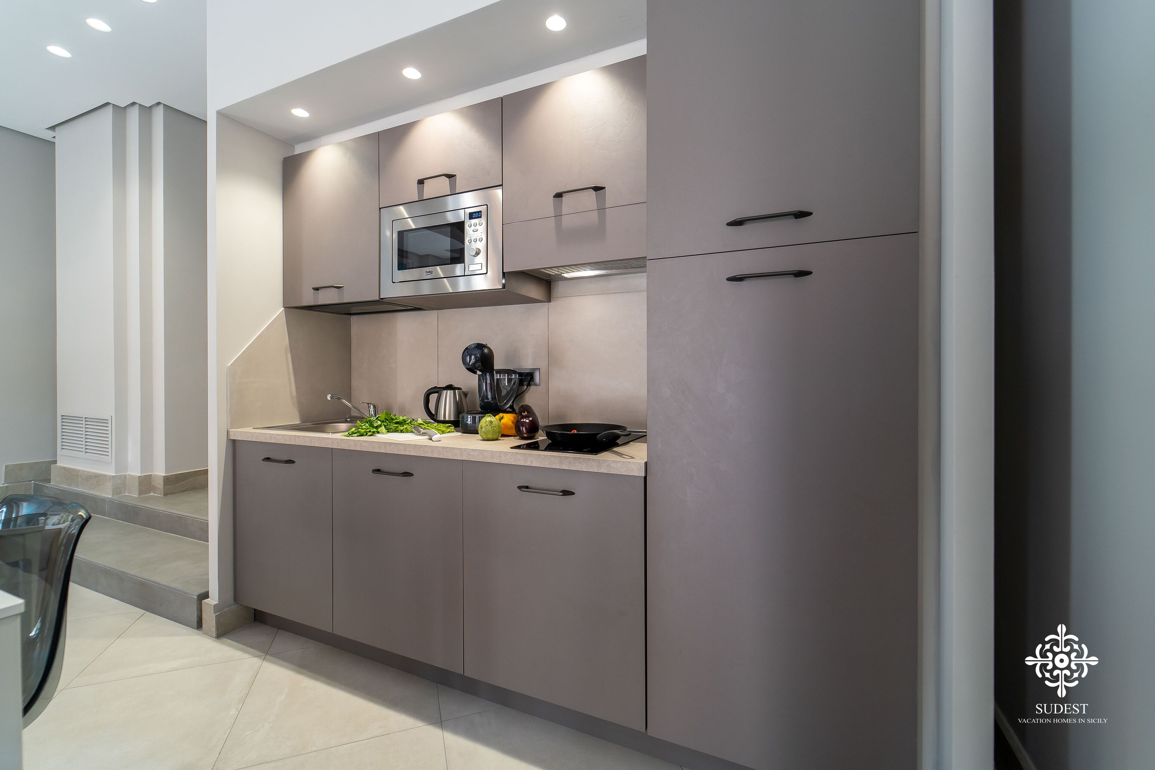 Una cocina moderna con armarios grises, un microondas y una cafetera.