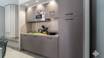Una cocina moderna con armarios grises, un microondas y una cafetera.