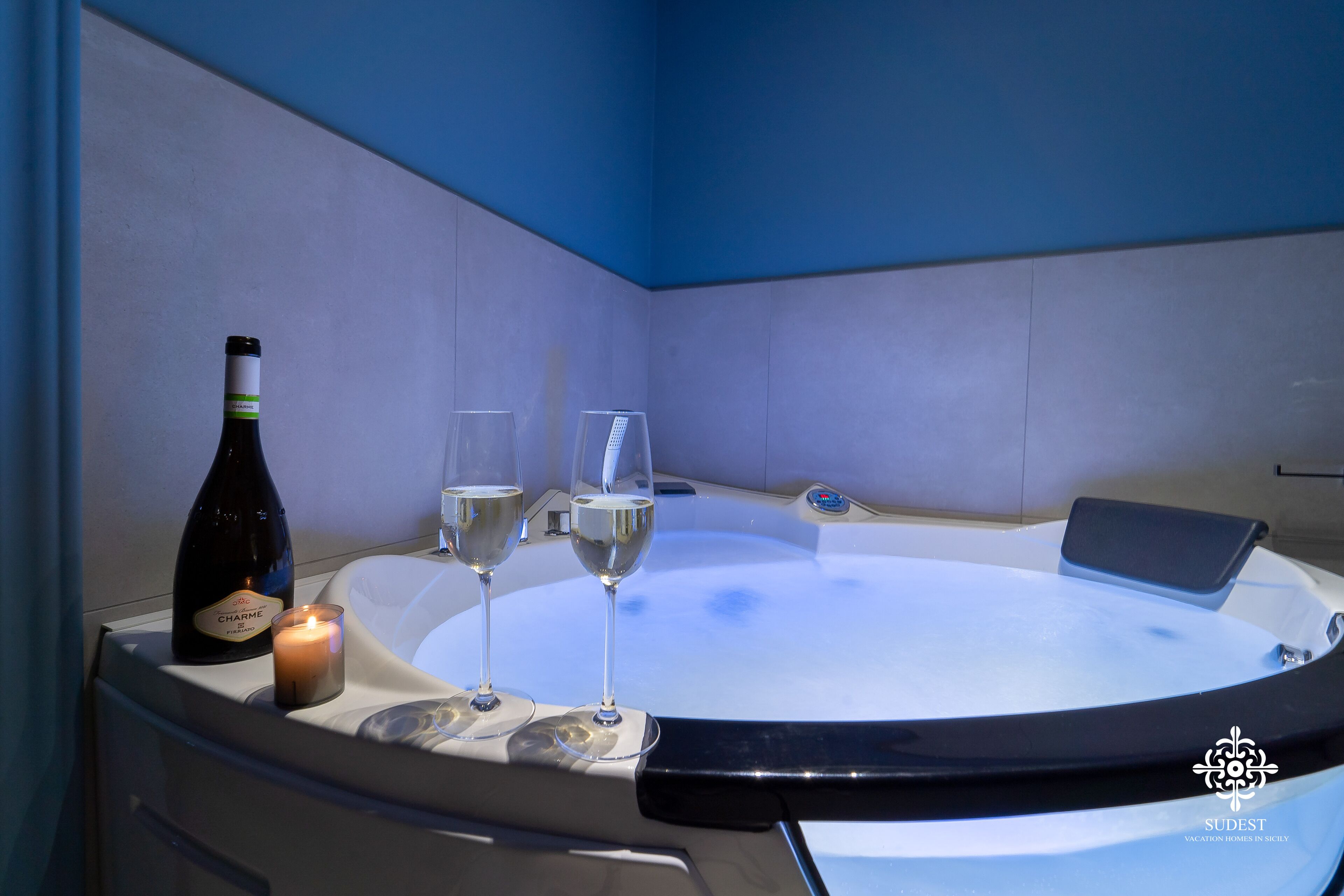 Ein Whirlpool mit zwei Weingläsern und einer Kerze.