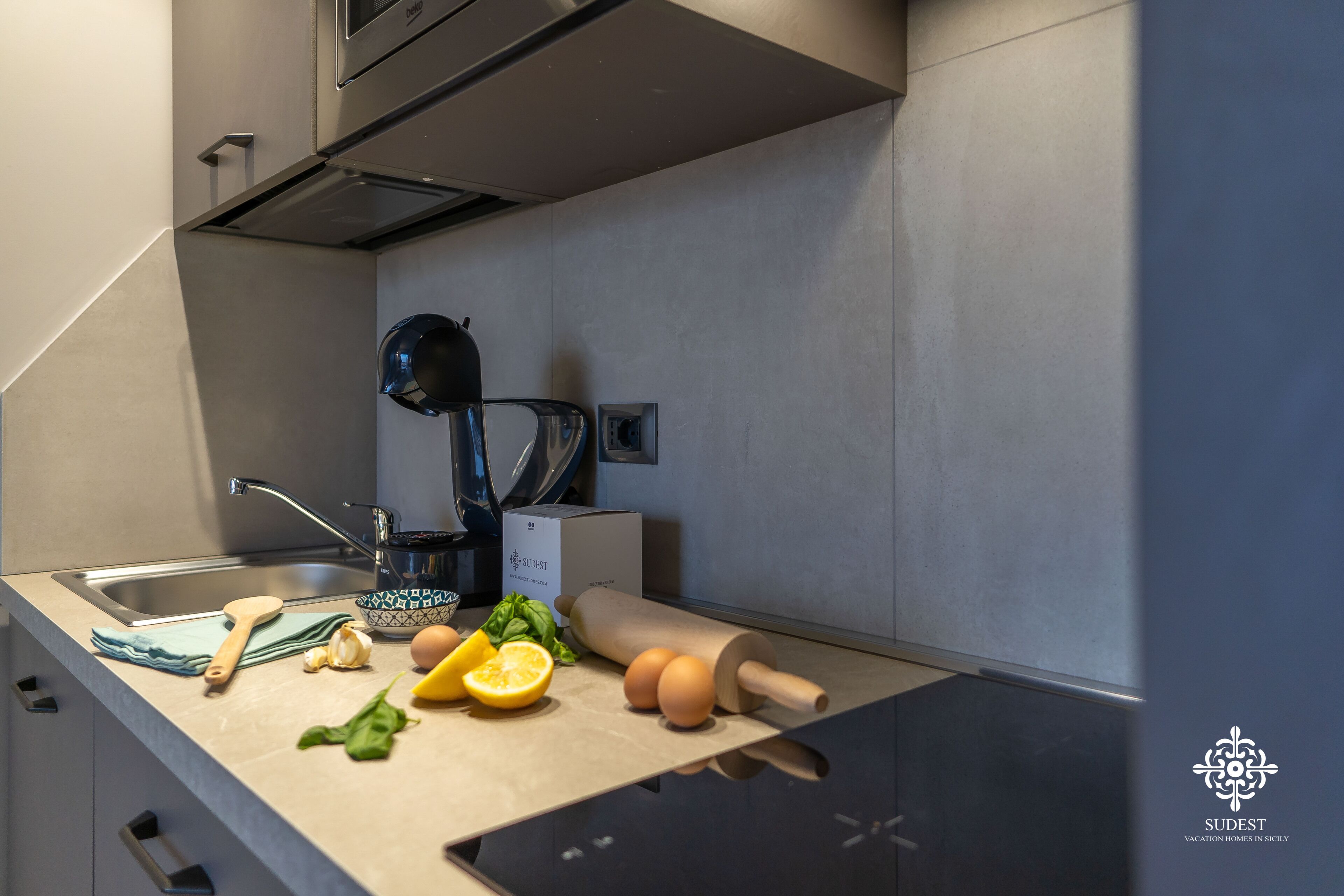 Een moderne keuken met een spoelbak, waterkoker, deegroller, eieren en vers fruit en groenten.