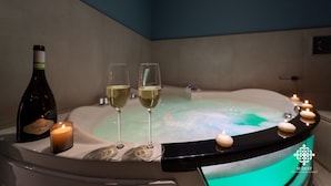 A hot tub with two glasses of white wine and a candle, surrounded by floating candles. - Matteotti Luxury Residence (Syracuse)