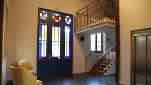 Een modern interieur met een blauwe deur, een trap en een gele stoel.