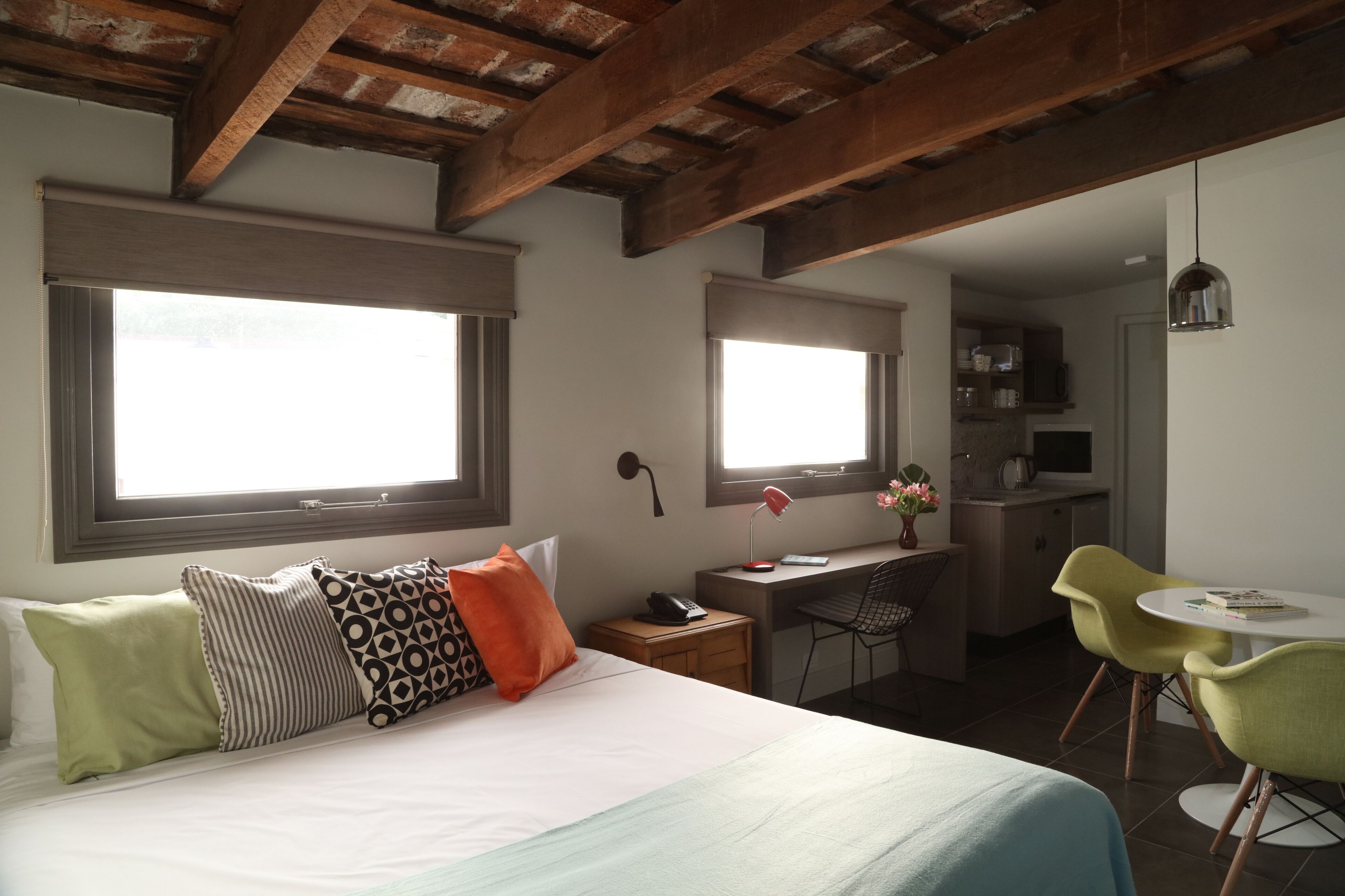 A bedroom with a bed, a desk, a chair, and a small dining table.
