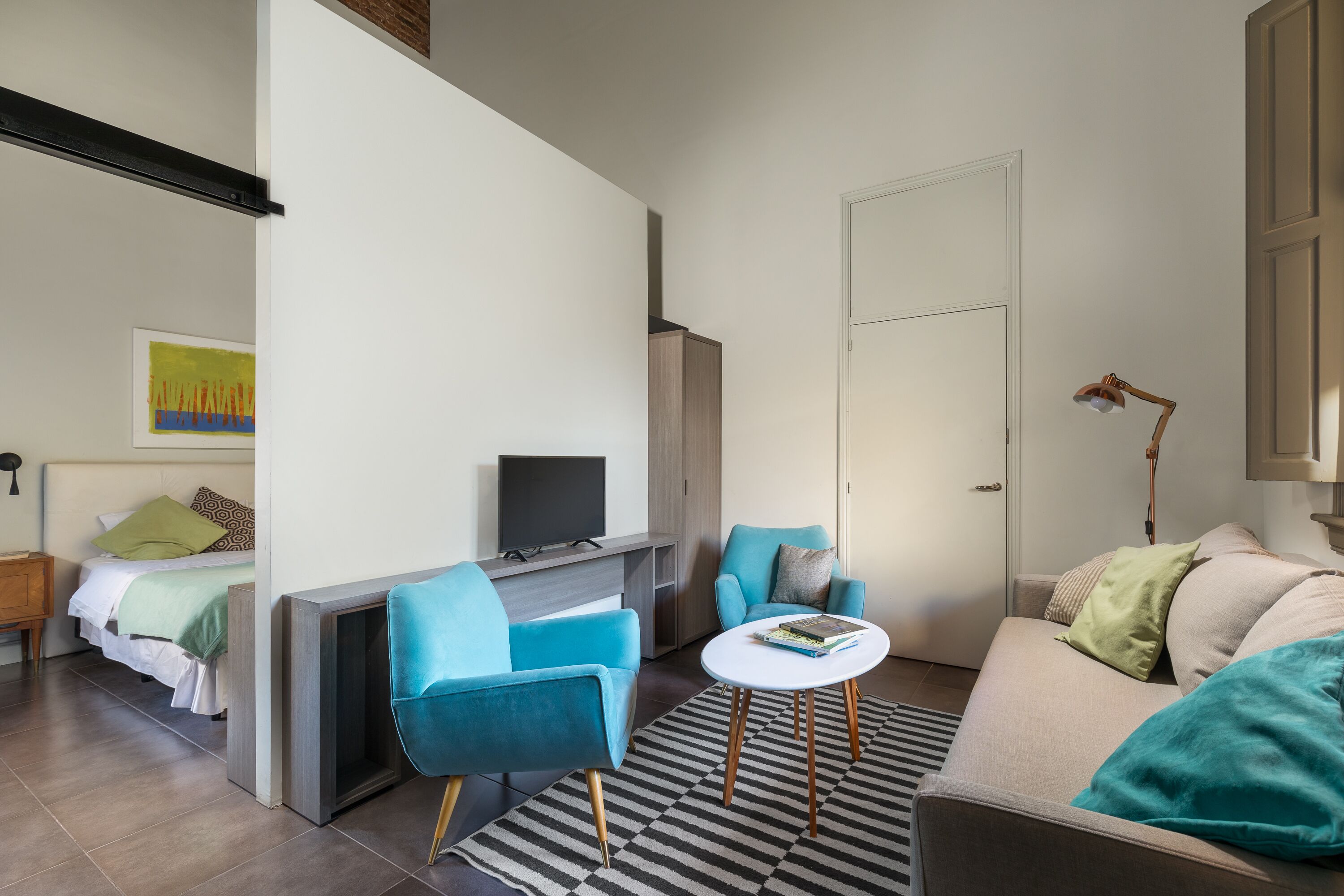A modern living room with a sofa, a coffee table, a TV, and a desk.
