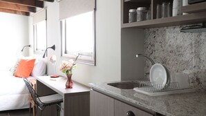 Een moderne keuken met een granieten aanrecht, een afwassigheid en een raam met zonwering.