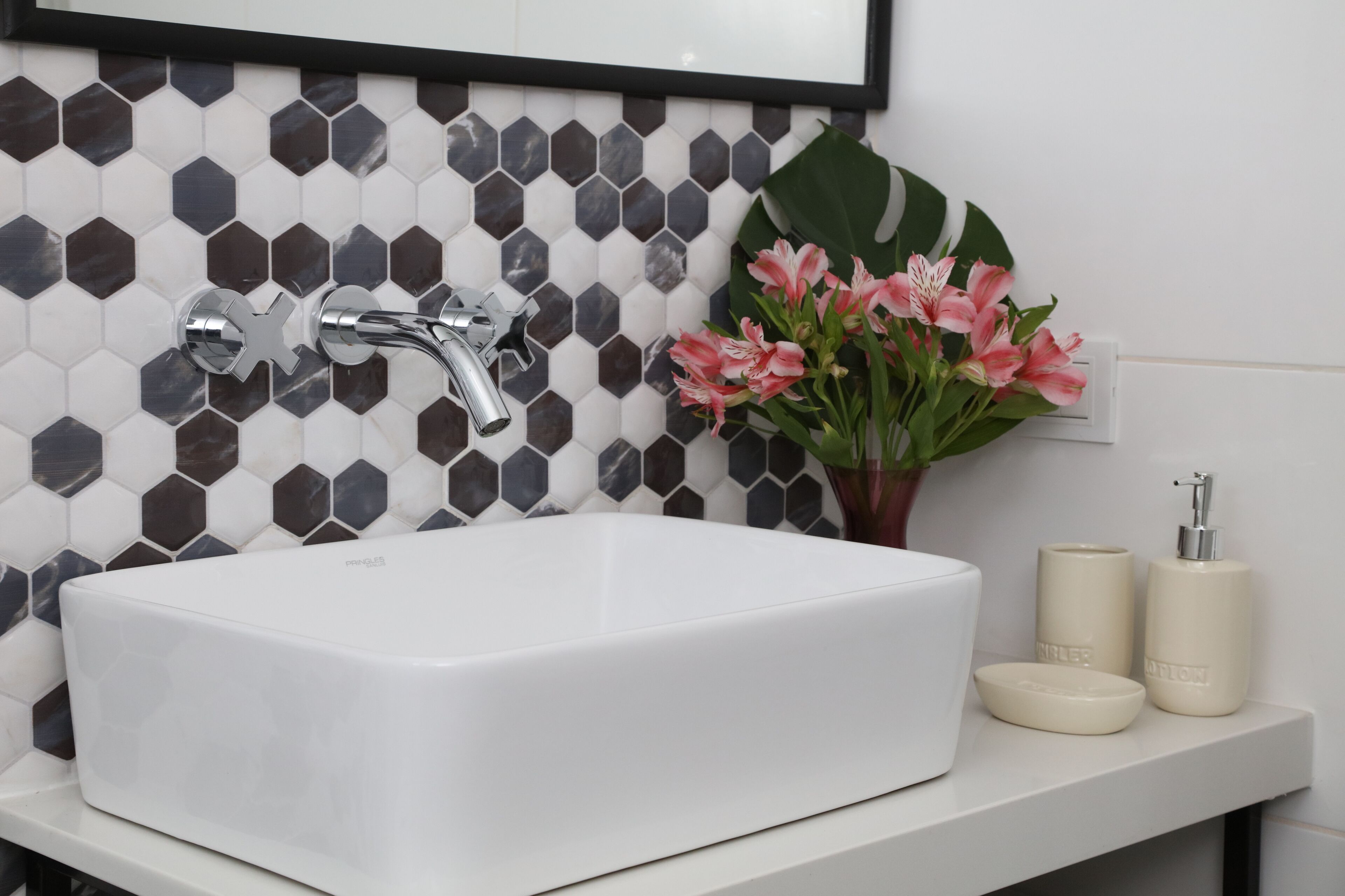 A bathroom with a white sink, a modern faucet, and a tiled backsplash.