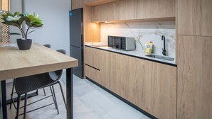 A modern kitchen with wooden cabinets, a black refrigerator, a microwave, and a sink. - Cadiz Magnolia Apartment (Cádiz)