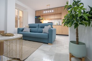 A modern living room with a blue sofa, a round coffee table, and a potted plant.