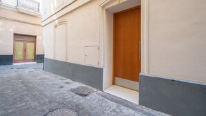 A building with a beige facade, a wooden door, and a small entrance. - Cadiz Magnolia Apartment (Cádiz)