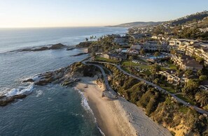 A coastal resort with a beachfront, a winding road, and a large building complex.