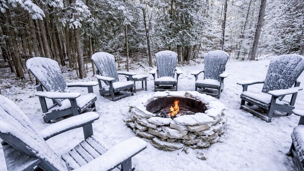 A snow-covered outdoor seating area with Adirondack chairs arranged around a stone fire pit. - Group Retreat | Hot Tub, Arcades, Private Trails (Ephraim)