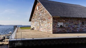 A wooden building with a sloped roof, covered in colorful stickers, located by a body of water. - Group Retreat | Hot Tub, Arcades, Private Trails (Ephraim)