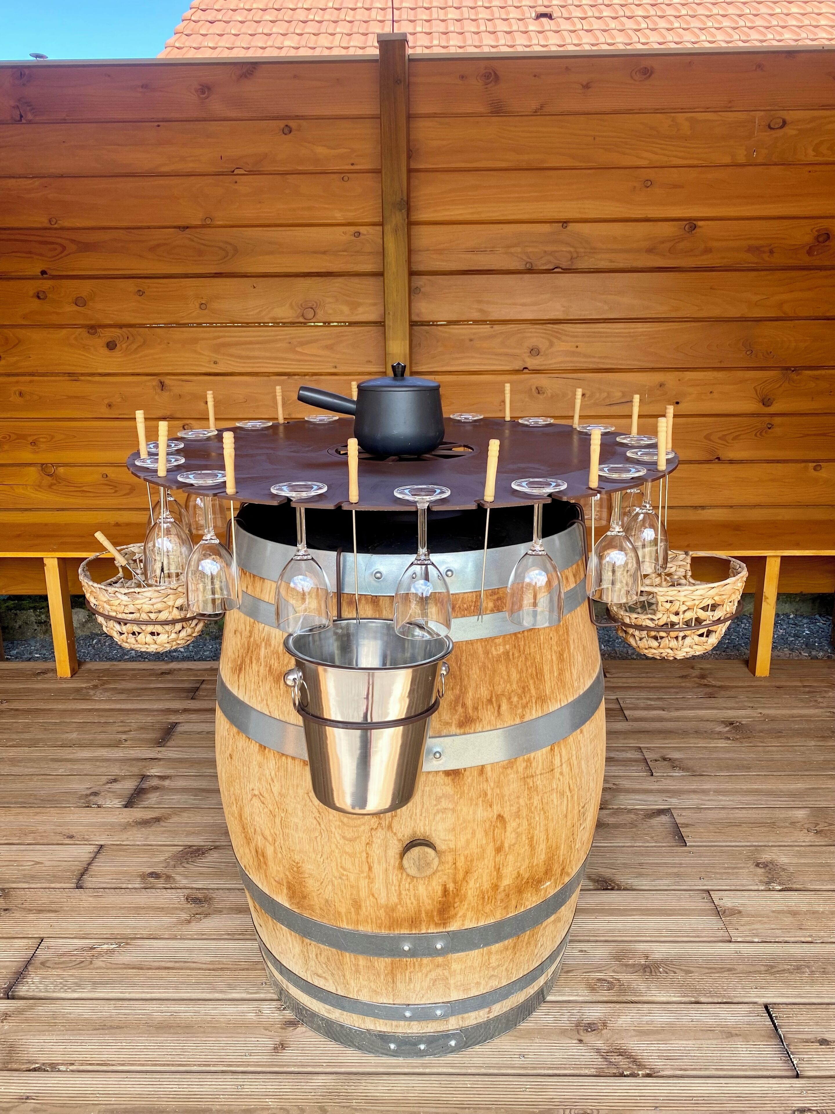 Una mesa de madera con barril, con un cubo metálico en el centro, rodeada de copas de vino y velas.