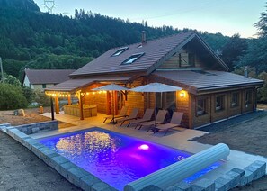 A wooden cabin with a swimming pool, outdoor seating, and a view of a forested hillside. - Chalet Pour 11 Personnes Hautes Vosges (Plainfaing)