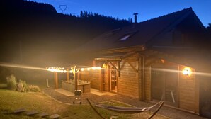 En stuga av trä med en veranda, en hängmatta och ljusslingor.