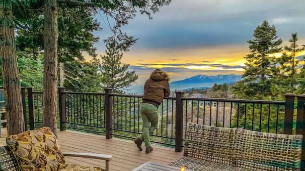A deck with a fire pit, outdoor furniture, and a view of mountains and a sunset. - Relax with spectacular views @ Bear Dance Cabin (Running Springs)