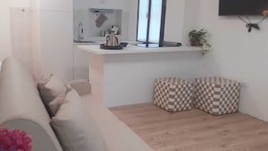 A modern kitchen with a white countertop, a sink, and a window. There are two checkered ottomans and a potted plant on the floor. - Magda's Corner-directly on the lake-private beach is private parking (Lombardia)