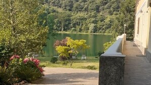 A paved pathway leading to a building with a stone pillar and a flower bed with pink flowers. - Magda's Corner-directly on the lake-private beach is private parking (Lombardia)