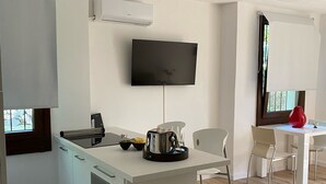 A modern kitchen with a built-in oven, a coffee maker, and a flat-screen TV mounted on the wall. - Magda's Corner-directly on the lake-private beach is private parking (Lombardia)