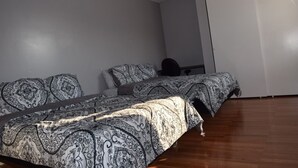 A bedroom with a large bed, a desk, and a wardrobe.