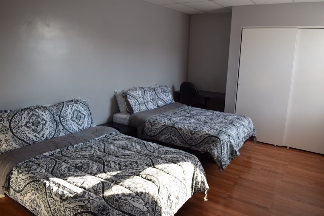 A bedroom with two beds, a desk, and a wardrobe.