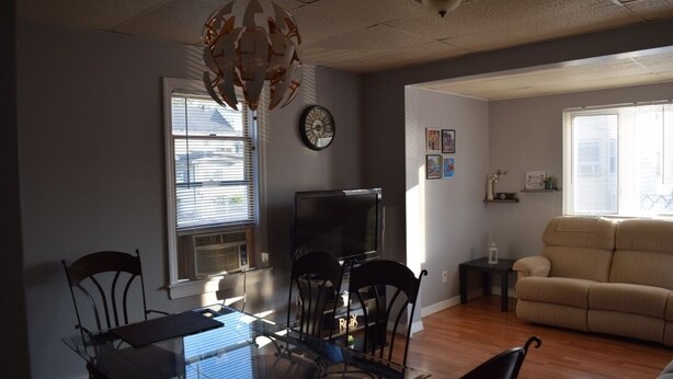 A living room with a sofa, a TV, and a dining area with chairs and a table.