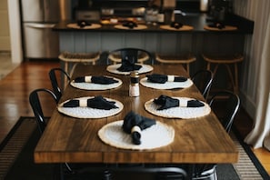 A dining table set with placemats, black napkins, and a salt and pepper shaker.