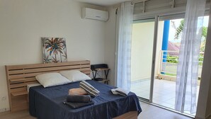 A bedroom with a wooden bed, a desk, and a view of the outdoors through a sliding door.