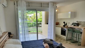 A bedroom with a bed, a desk, and a view of a garden through a sliding door.