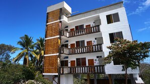 A multi-story building with balconies, wooden railings, and a clear blue sky. - Isla Azul Hotel (Puerto Ayora)