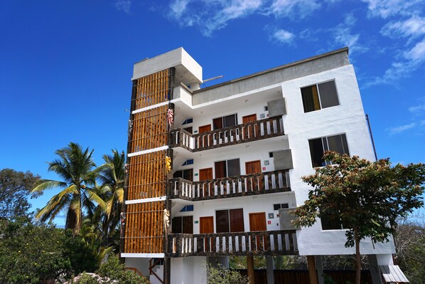 A multi-story building with balconies, wooden railings, and a clear blue sky. - Isla Azul Hotel (Puerto Ayora)