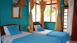 A room with two beds, a mirror, and a window with curtains. - Isla Azul Hotel (Puerto Ayora)