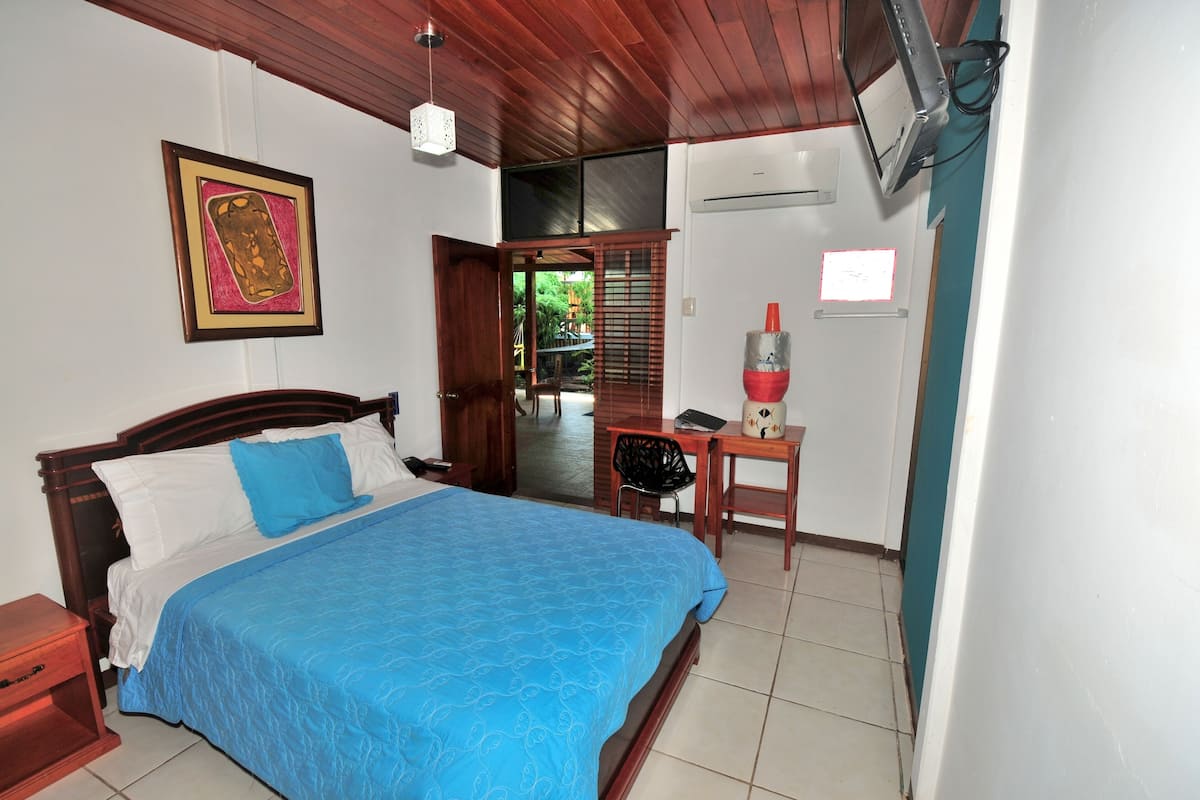 A bedroom with a bed, a desk, and a chair.