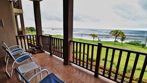 A balcony with chairs overlooking a grassy area and the ocean. - Suite San Juan 125 Gran Pacifica Resort (Villa El Carmen)