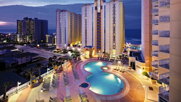 Un hotel con una piscina grande, varios edificios altos y vistas al océano.