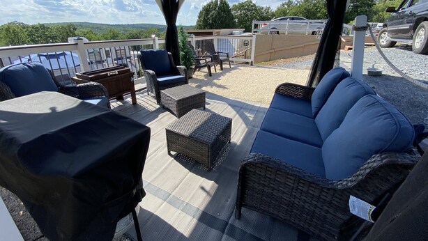 An outdoor patio with wicker furniture, a covered seating area, and a view of the surrounding landscape.