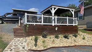 A covered outdoor area with a wooden deck, a stone pathway, and a small garden with rocks and plants.