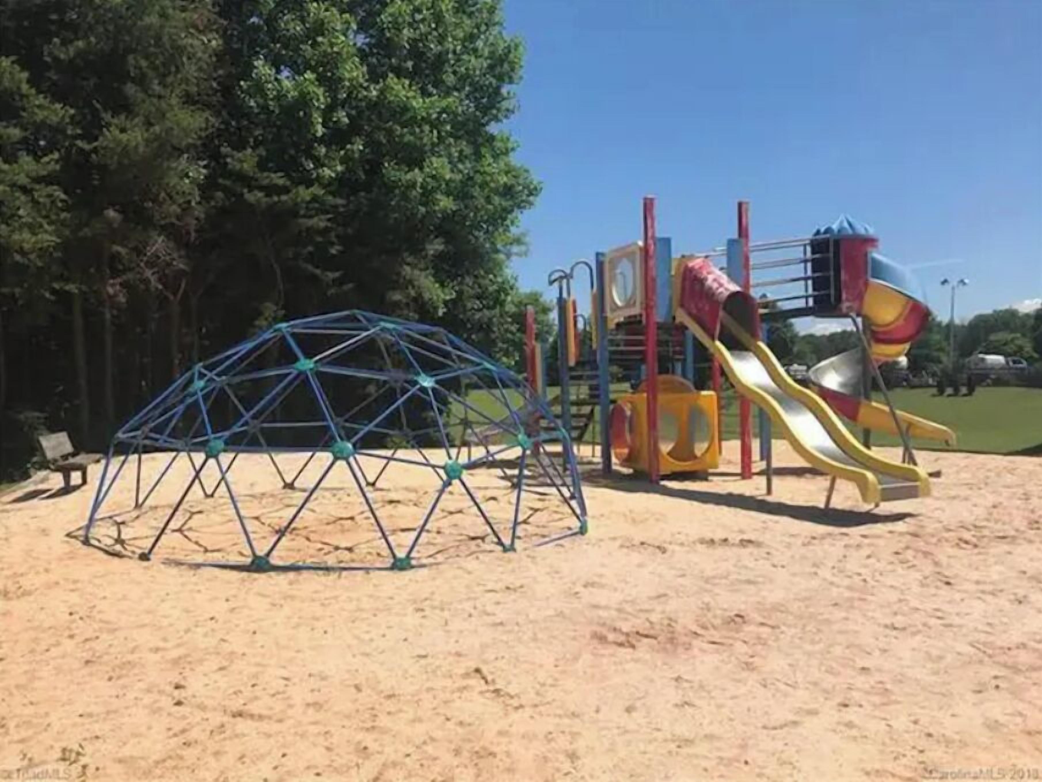 A playground with a geodesic dome structure and a colorful slide.