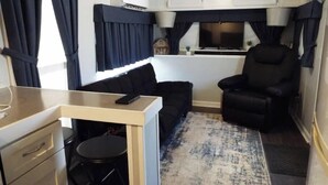 A compact living space with a kitchenette, a sofa, a chair, and a small table.