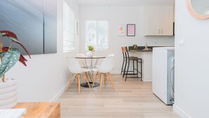 A modern kitchen with white cabinets, a dining area with a table and chairs, and a washing machine.