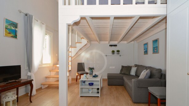 Ein Wohnzimmer mit Fernseher, Sofa und Treppe.